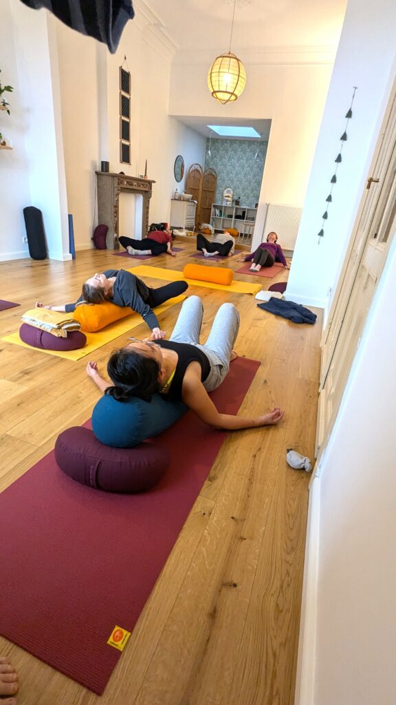 Séance de Yin Yoga à Braine-Le-Comte. Les gens sont détendus et étirent leur dos sur un rouleau de Yoga.